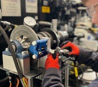A man in a lab focused on repairing a complex machine, surrounded by tools and equipment.