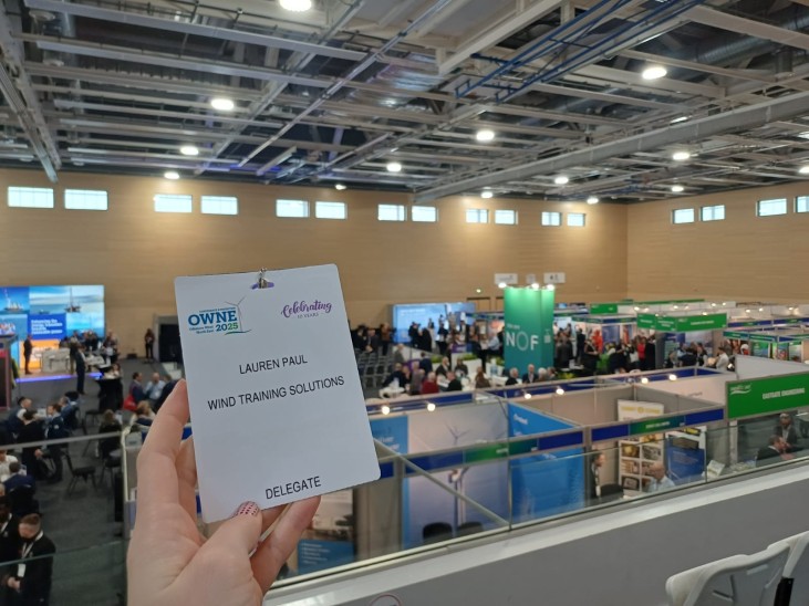 A delegate badge in front of the conference hall for OWNE 2025.